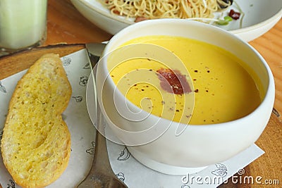 Yellow pumpkin soup with garlic bread serving on the timber block Stock Photo