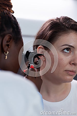 Closeup of african american otologist doctor analyzing woman patient ear Stock Photo
