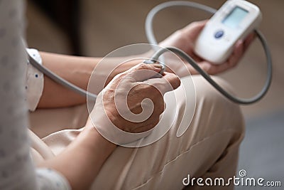 Closeup aged woman using sphygmomanometer checking arterial pressure at home Stock Photo
