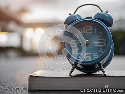 Closeup alarm clock on book with sunset background. Stock Photo