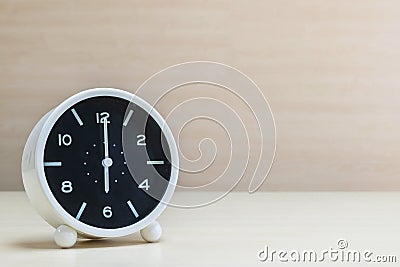 Closeup alarm clock for decorate in 6 o`clock on brown wood desk and wall textured background with copy space Stock Photo