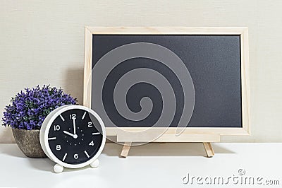 Closeup alarm clock for decorate show 10 o`clock with wood black board on white wood desk and cream wallpaper textured background Stock Photo