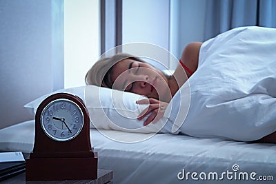 Closeup alarm clock having a good night with background happy woman sleeping in bed Stock Photo