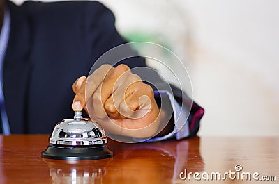 Closeup arm of man wearing blue suit pressing desk bell at hotel reception Stock Photo