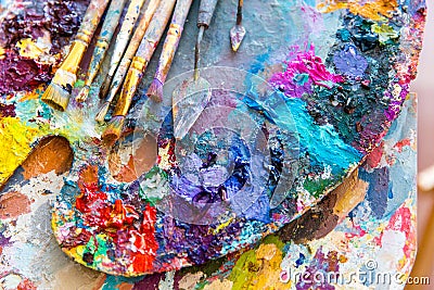Closeup of art palette with colorful mixed paints and paintbrushed Stock Photo