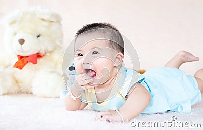 Closeup asian baby infant laying comfortably on bed playing with bear doll on softness cushion,Baby development concept Stock Photo