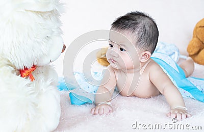 Closeup asian baby infant laying comfortably on bed playing with bear doll on softness cushion Stock Photo