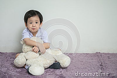 Closeup asian kid with boring face with bear doll sit on carpet with copy space Stock Photo