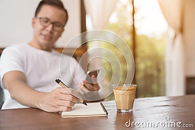 closeup asian male hand is writing a note in a cafe,Choose a focal point at the hands of men Stock Photo