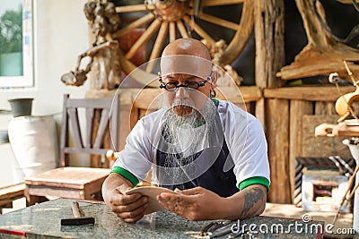 Closeup Asian man leather product maker looking at pieces leather skins to make products in his shop Stock Photo