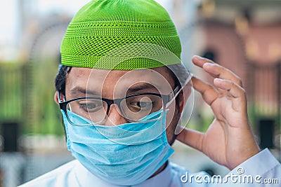 Closeup Asian Muslim man in traditional attire with face mask Stock Photo
