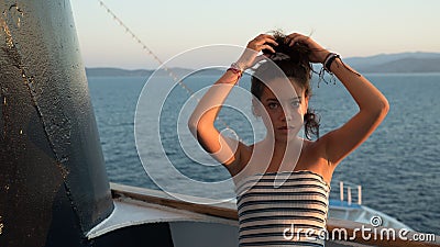 Closeup of Asian teen in striped tube top leaning against railing and fixing her hair Stock Photo