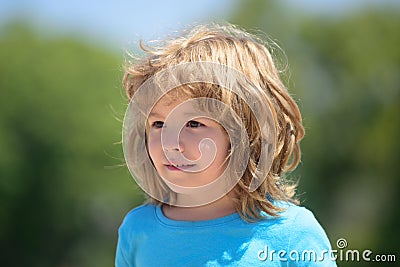 Closeup attractive kids face. Child emotions concept. Portrait of young smiling kid outdoor. Blur background. Stock Photo