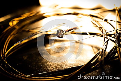 Closeup of Ball End on Guitar String Surrounded by Circle of Used Loose Guitar Strings Stock Photo