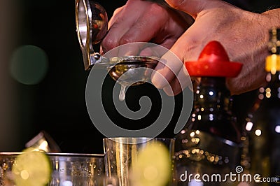 Closeup bartender hand preparing fresh juice cocktail in drinking wine glass with ice at night bar clubbing counter. Occupation Stock Photo