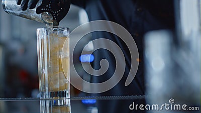 Closeup bartender hands pouring cocktail in glass. Mixologist preparing beverage Stock Photo