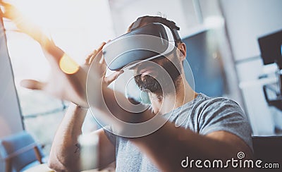 Closeup of bearded young man wearing virtual reality goggles in modern coworking studio. Smartphone using with VR Stock Photo