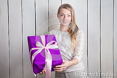 Closeup beautiful blond girl shows at camera large purple gift box holding in hands Stock Photo