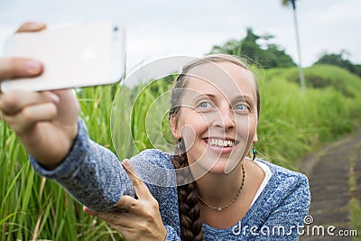 Closeup of beautiful woman taking a selfie on smart phone outdoors in summer. Young woman photographing herself smiling. Stock Photo