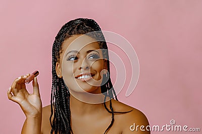 closeup beauty headshot of young adult black woman with pink gloss lipstick on studio background looking away at copy Stock Photo