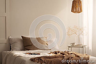 Closeup of bed with beige blanket and linen pillow in minimal bedroom interior, real photo Stock Photo