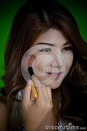 Closeup Beutiful model enjoy makeup applies brusher on her face. Stock Photo