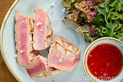 Closeup Medium rare tuna with lettuce and hot sauce. Restaurant menu Stock Photo