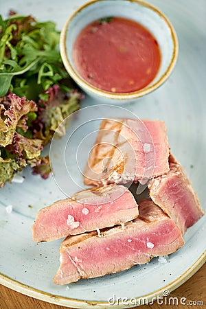 Closeup Medium rare tuna with lettuce and hot sauce. Restaurant menu Stock Photo