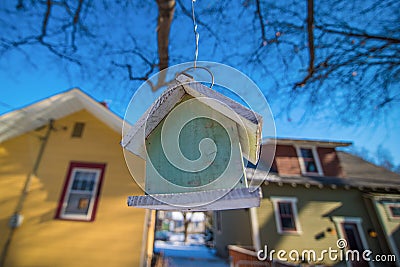 Closeup of a bird house between two real houses - blue skies and overhanging tree - city neighborhood Stock Photo