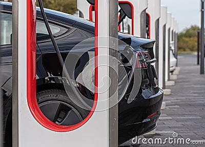 Closeup of a black charging Tesla car by Tesla Supercharger in Wetzlar, Germany Editorial Stock Photo