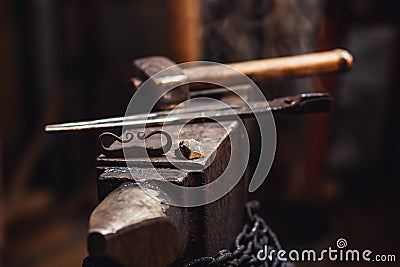 Closeup of a blacksmith anvil with a hammer, tongs, firesteel and flint. Stock Photo