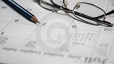Closeup blue pencil and glasses on a calendar, business and finance concept Stock Photo
