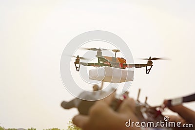 Closeup of blurred hands operating drone transmitter, receiver controller, controller in out of focus while drone is in focus at Stock Photo