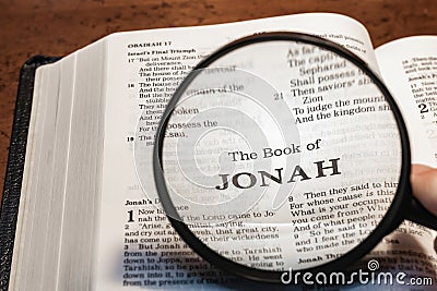 closeup of the book of Jonah from Bible or Torah using a magnifying glass to enlarge print. Stock Photo