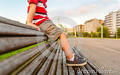 Boy legs sitting on the top of bench park relaxing Stock Photo