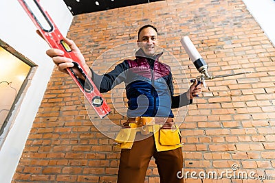 Closeup of bricklayer hands holding hardhat and construction equipment. Handyman with tools belt Stock Photo