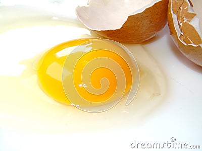 Closeup of broken raw egg, yolk and white next to eggshells Stock Photo