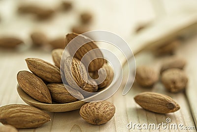 Closeup of brown fresh almonds seed in wooden spoon on wooden table Stock Photo