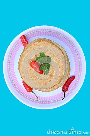 closeup the bunch brown color frayed tortilla with red chilly and green mint in the plastic plate on the sky background Stock Photo