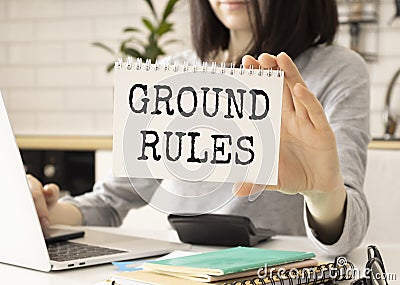 Business woman holding a card with text GROUND RULES, business concept image with soft focus background and vintage Stock Photo