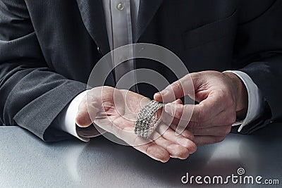 Closeup on businessman hands displaying precious metal jewel for concept of gold and money in hands Stock Photo