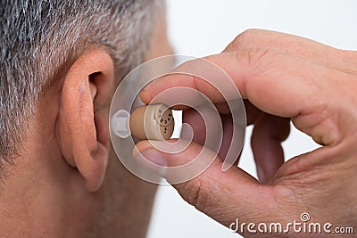 Closeup Of Businessman Inserting Hearing Aid In Ear Stock Photo