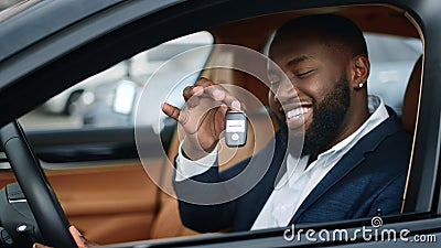 Closeup businessman shaking key in new car. African man smiling in vehicle Stock Photo