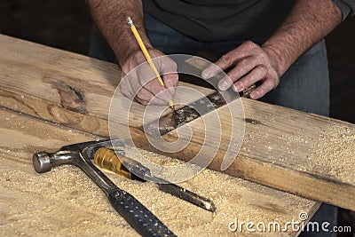 Closeup of carpenter marking line on wooded board with pencil and wooden square during home remodel Stock Photo