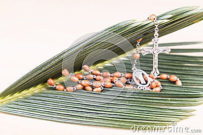 Closeup Catholic rosary with crucifix and beads on palm leaf Stock Photo