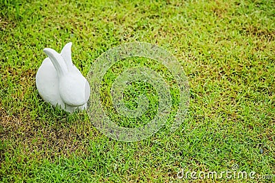 Closeup cement rabbit statue for decoration on grass floor in the garden background with copy space Stock Photo