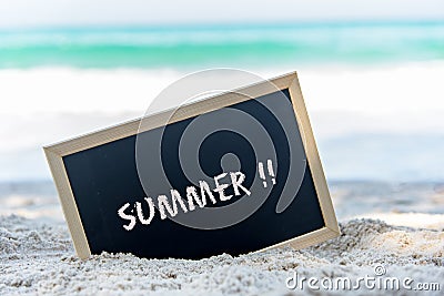 Closeup of a chalkboard with the text summer written on the sand of a beach. Stock Photo