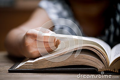 Closeup child hand opening and reading a book in library Stock Photo