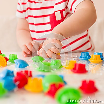 Closeup of child`s hand taking bright mosaic parts. Playing and learning colors at home. Toddler boy in a striped shirt Stock Photo