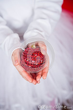 Closeup children`s hands holding red Christmas ball. Stock Photo